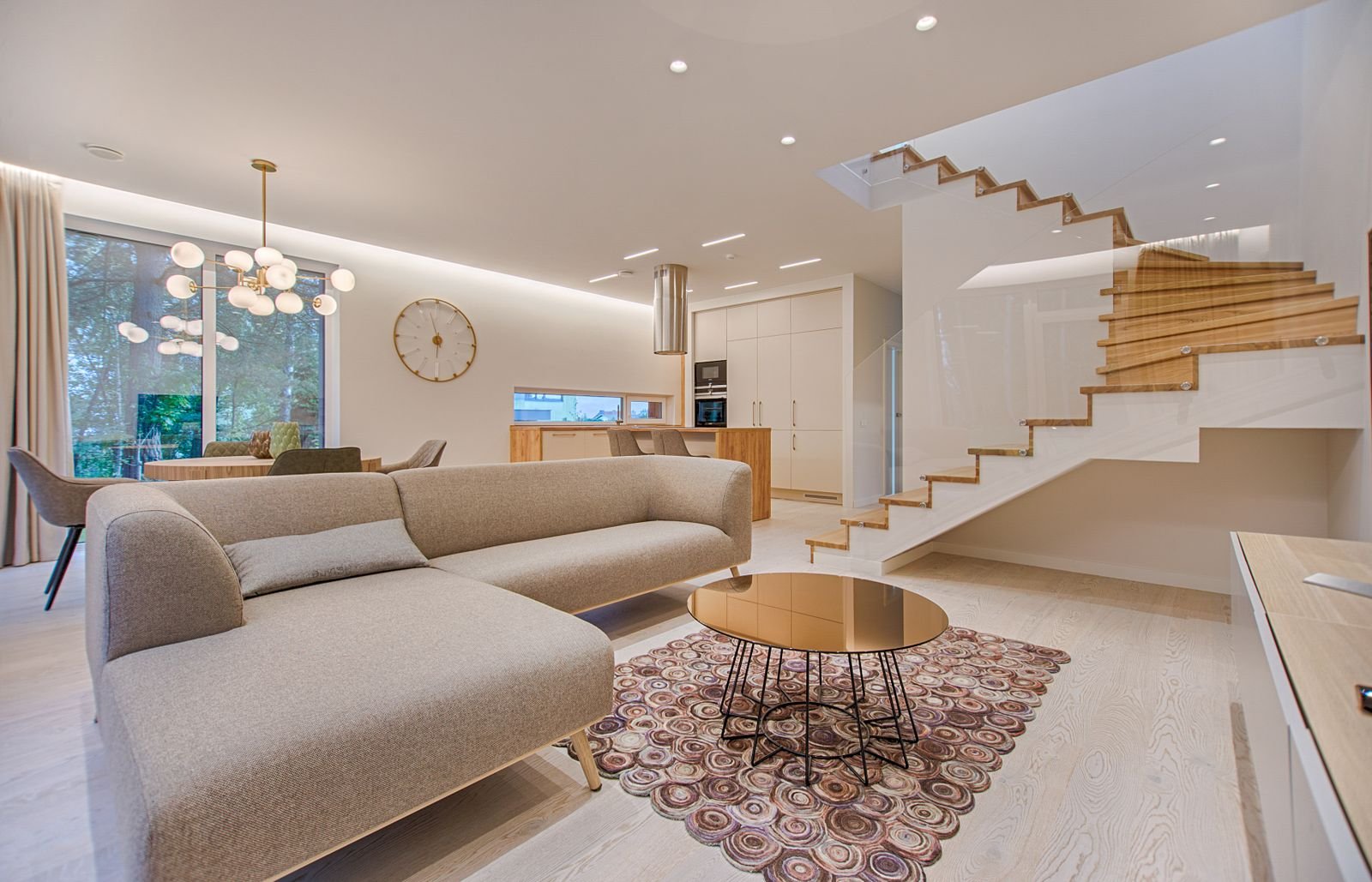 Living moderno con gran ventanal, escalera de madera y luz natural en una vivienda de diseño contemporáneo