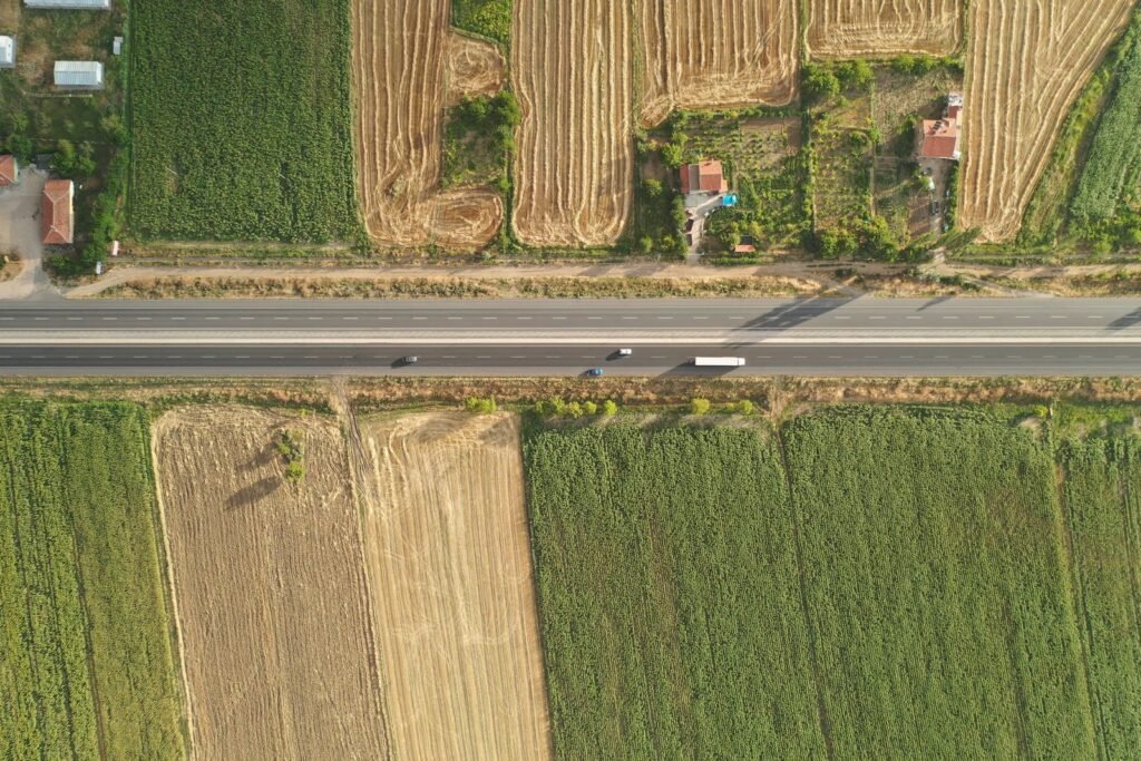 Vista aérea de campos cultivados en distintas parcelas, divididos por una ruta de acceso