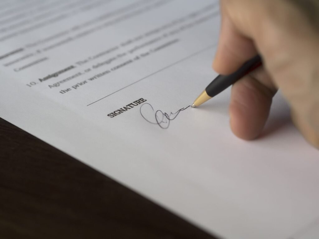 Mano firmando un contrato de alquiler con una lapicera sobre un documento impreso