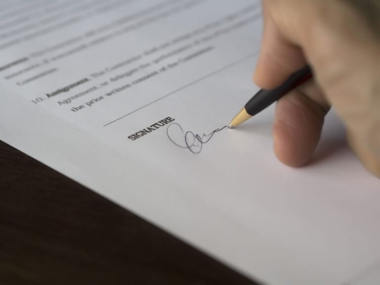 Mano firmando un contrato de alquiler con una lapicera sobre un documento impreso