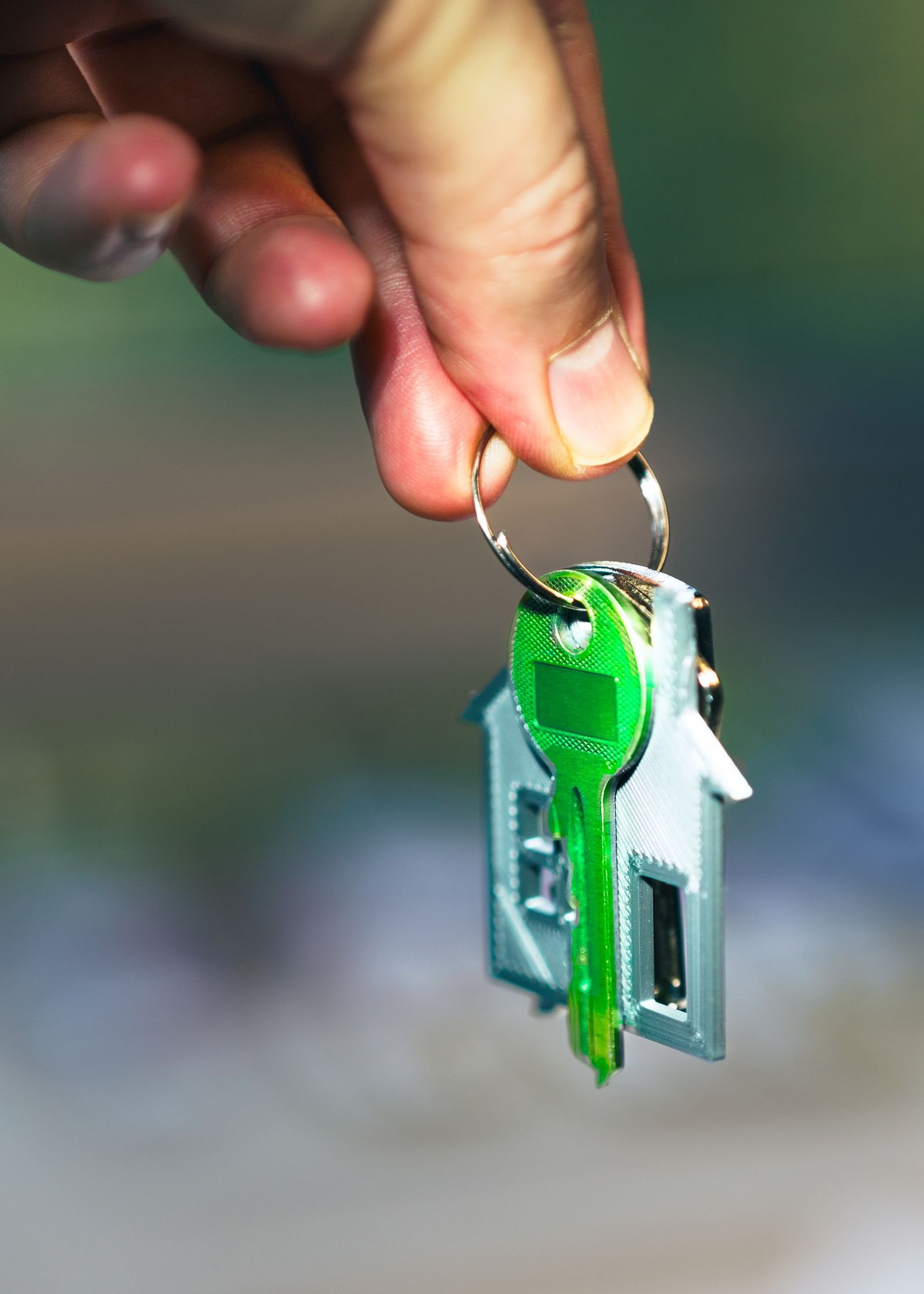 Mano sosteniendo un llavero con forma de casa y una llave verde