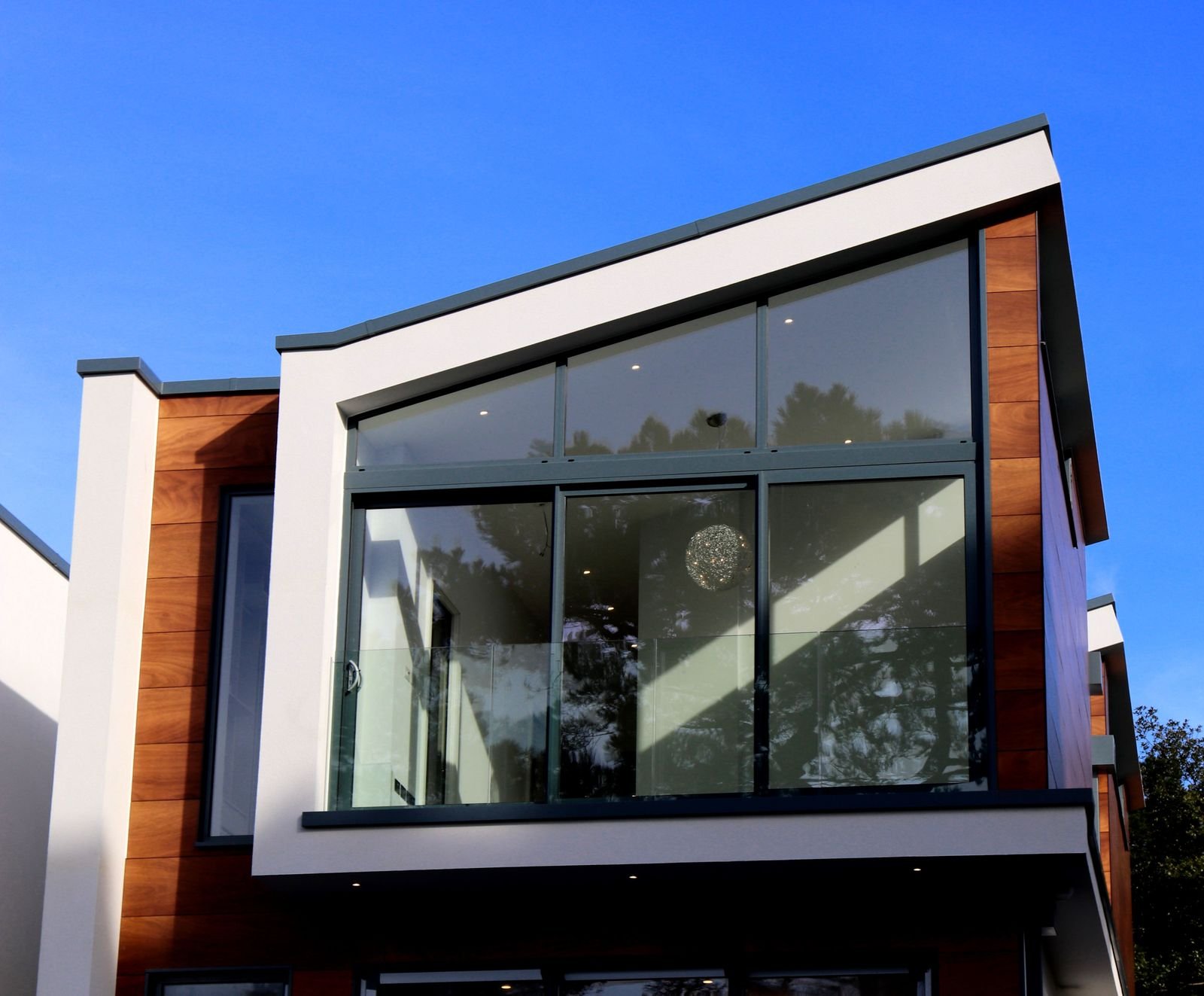 Detalle arquitectónico de fachada moderna con grandes ventanales, vidrio y revestimiento en madera