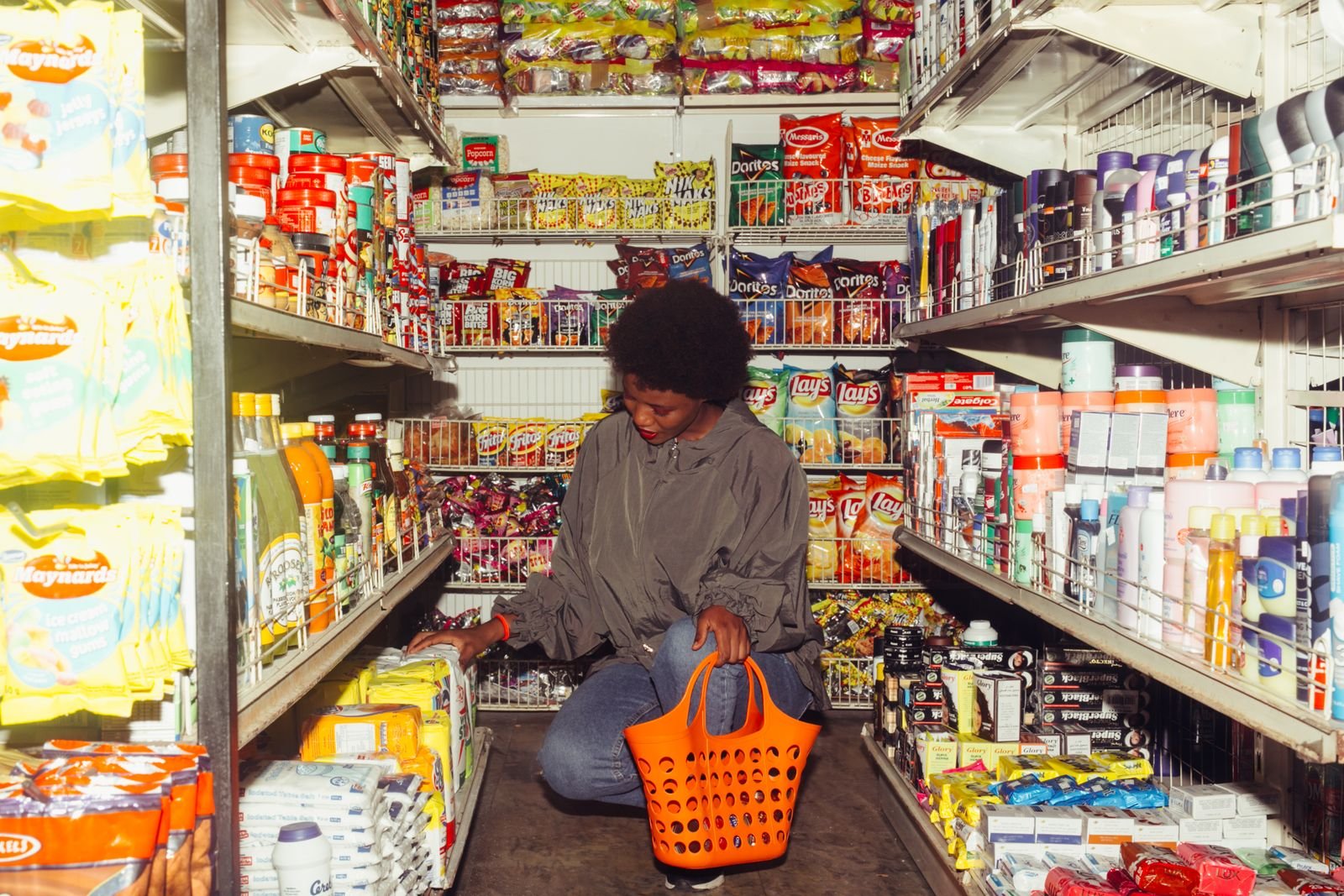 Interior de un local comercial minorista con estanterías de productos y clienta eligiendo mercadería