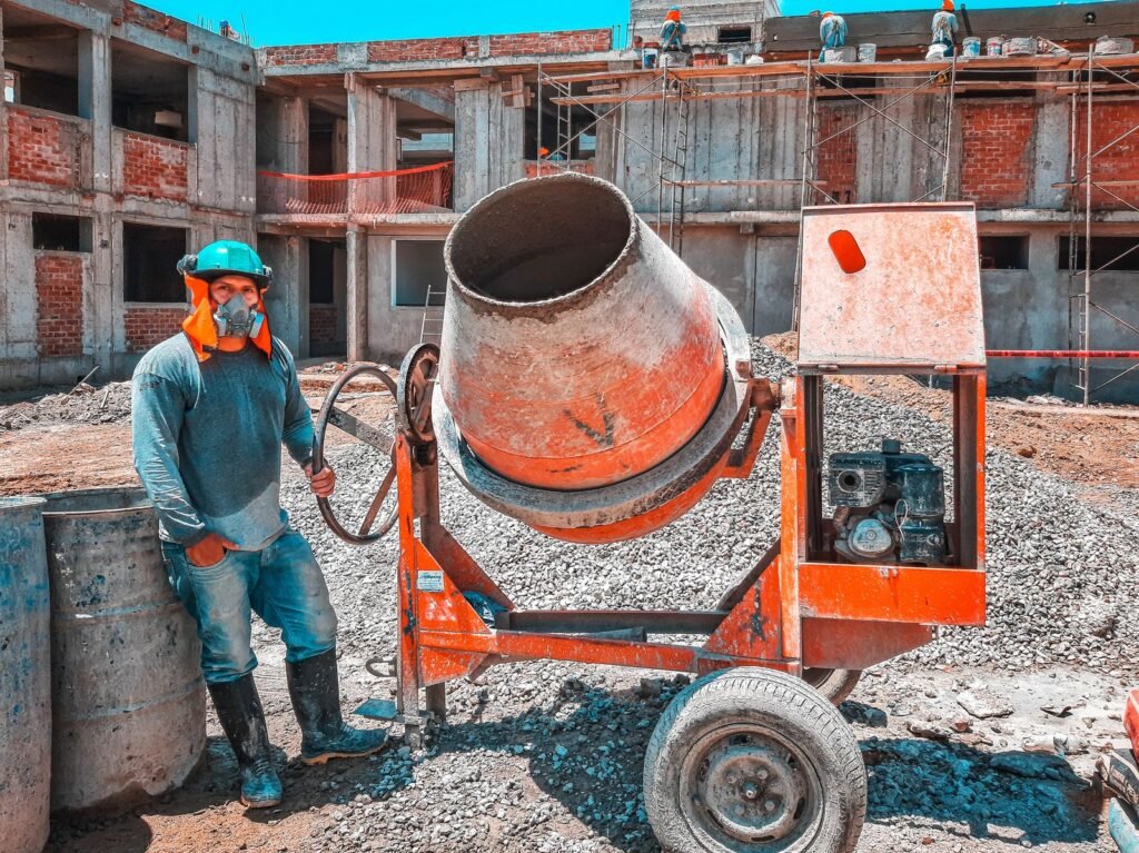Obra en construcción de un edificio de apartamentos en pozo, con obrero y mezcladora de hormigón