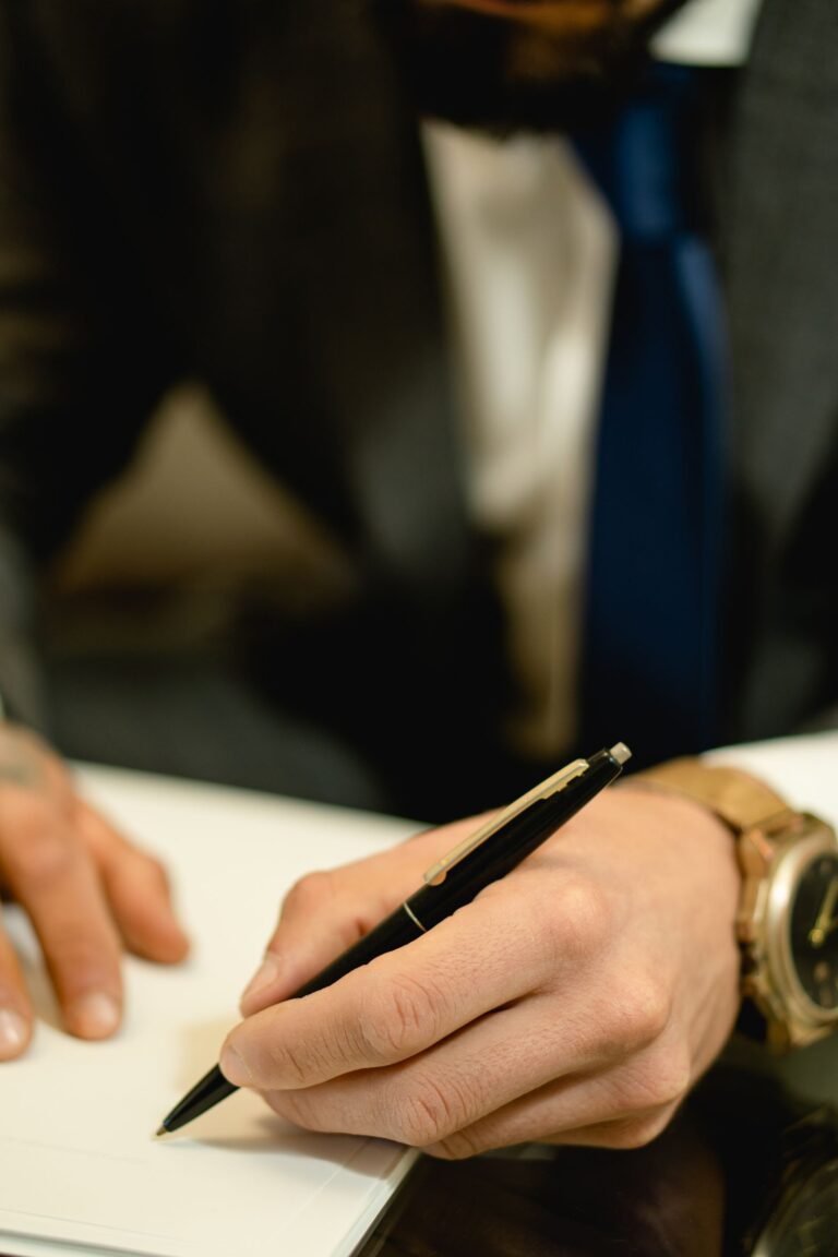 Mano firmando un documento con una lapicera, en un contexto formal de negocios